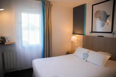 Un ou plusieurs lits dans un hébergement de l'établissement Kyriad Hôtel La Fleche